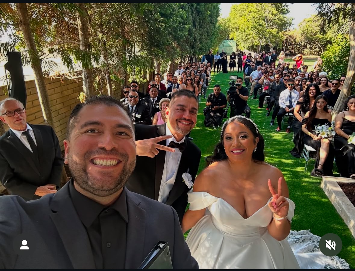 Mike taking a selfie with couple and entire wedding crowd giving peace signs