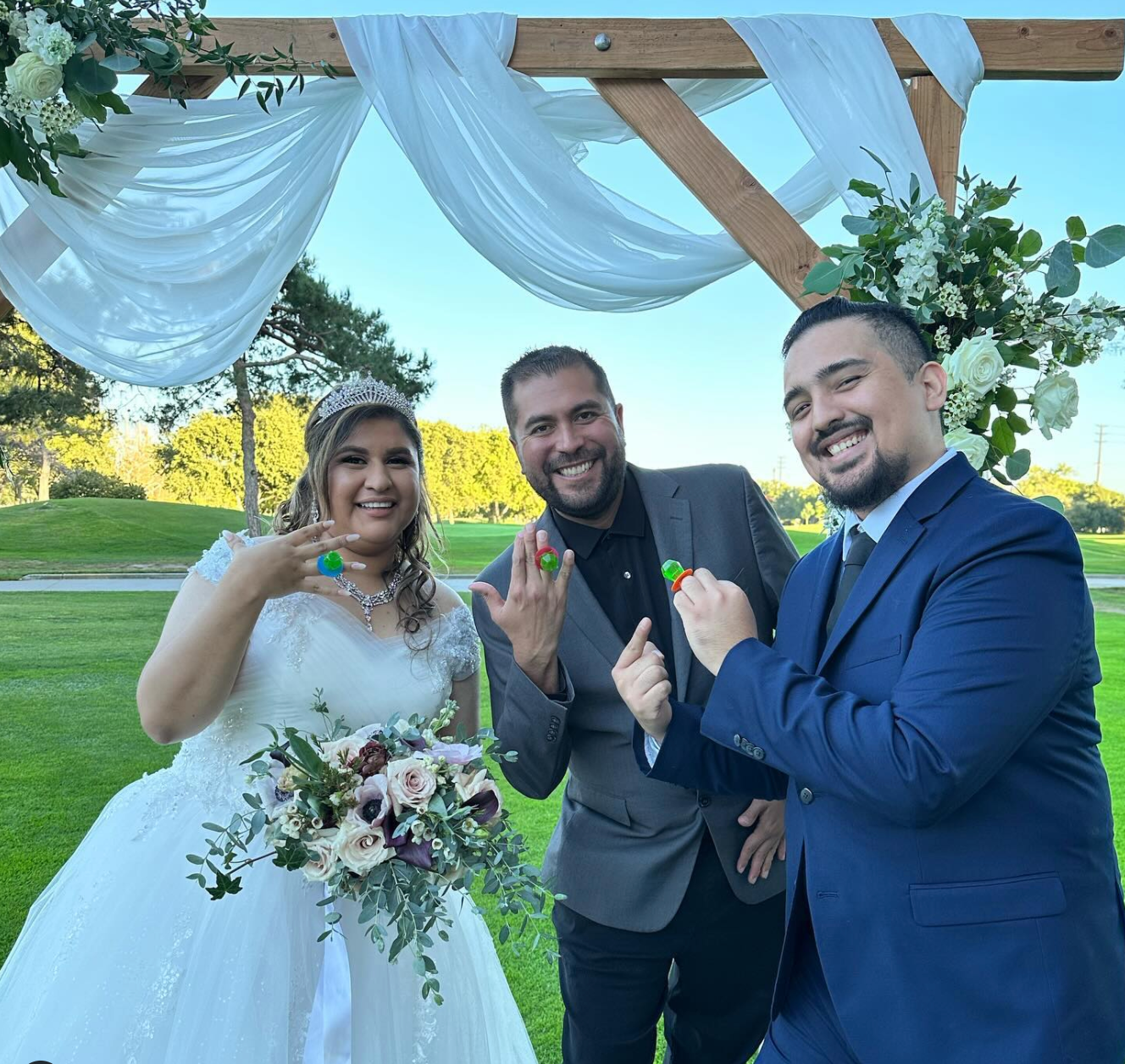 Mike and couple showing off gummy candy rings at a golf course ceremony