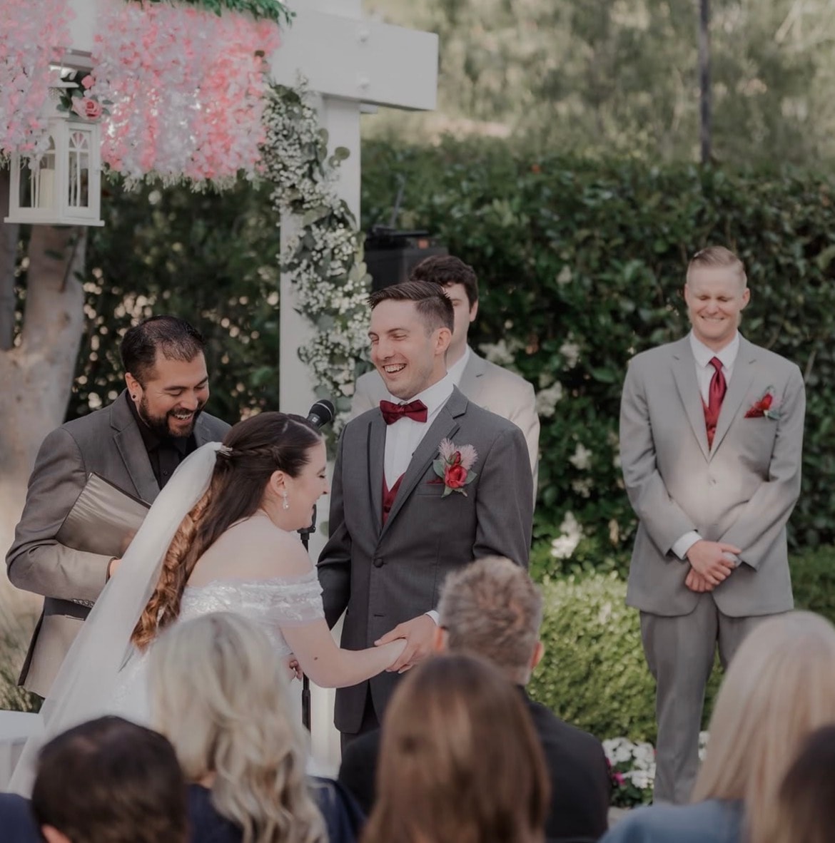 Mike laughing with bride and groom during vow exchange at an outdoor ceremony