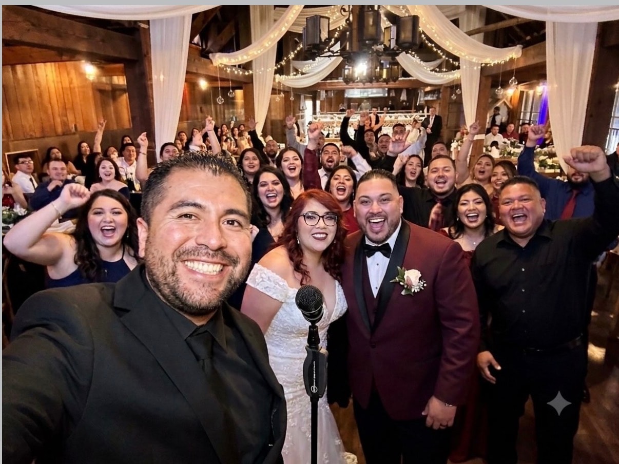 Mike celebrating with a newlywed couple and their guests at a wedding reception