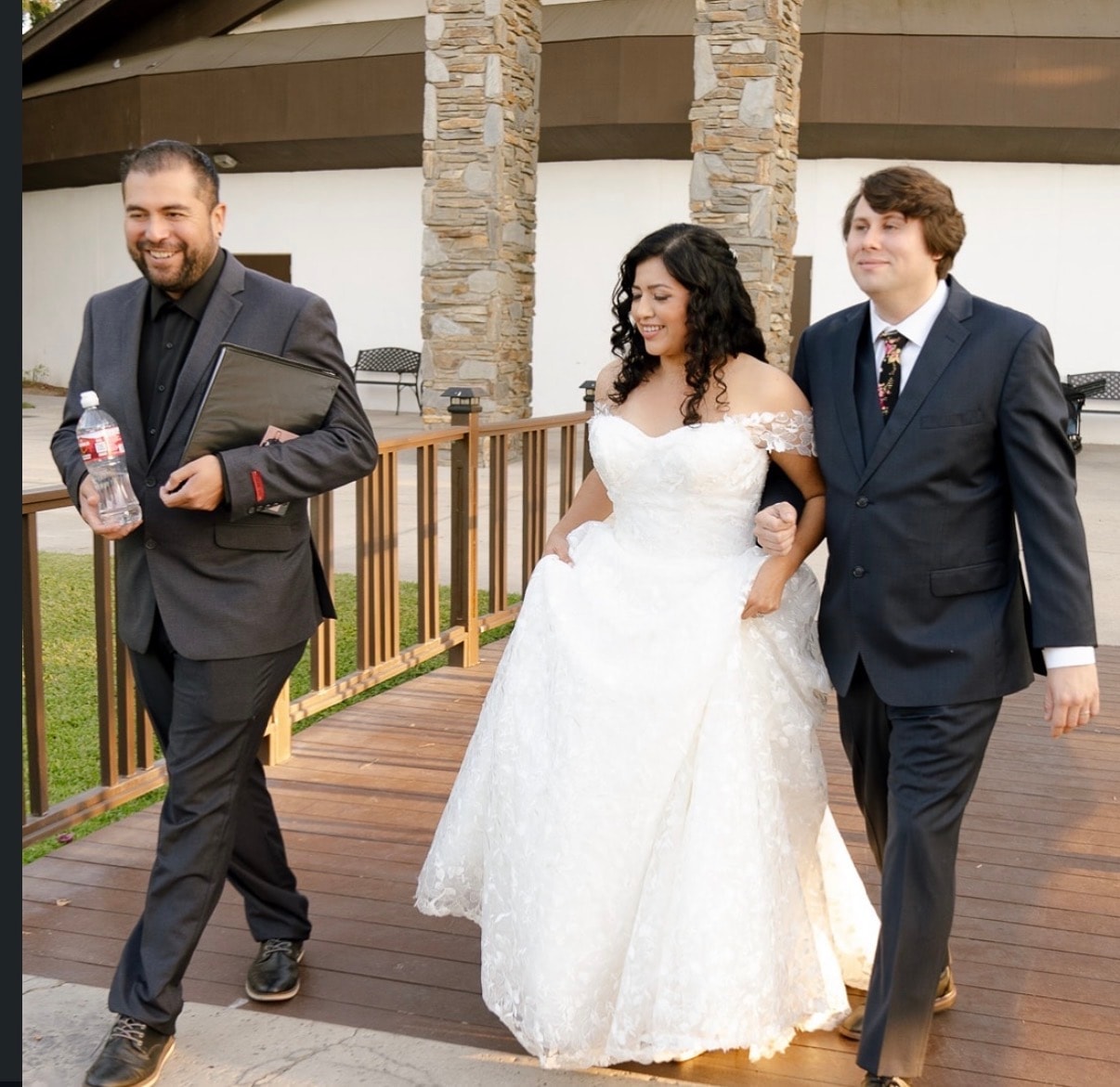 Mike walking with bride and groom on wooden deck after OC ceremony