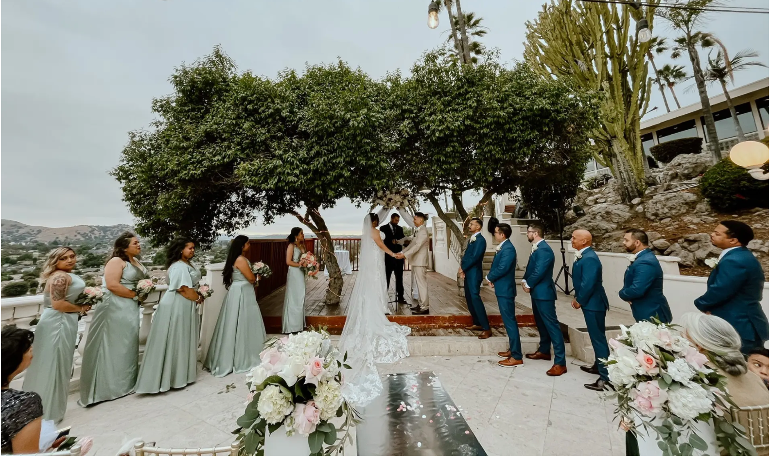 Full wedding party ceremony on a hillside terrace with mountain views