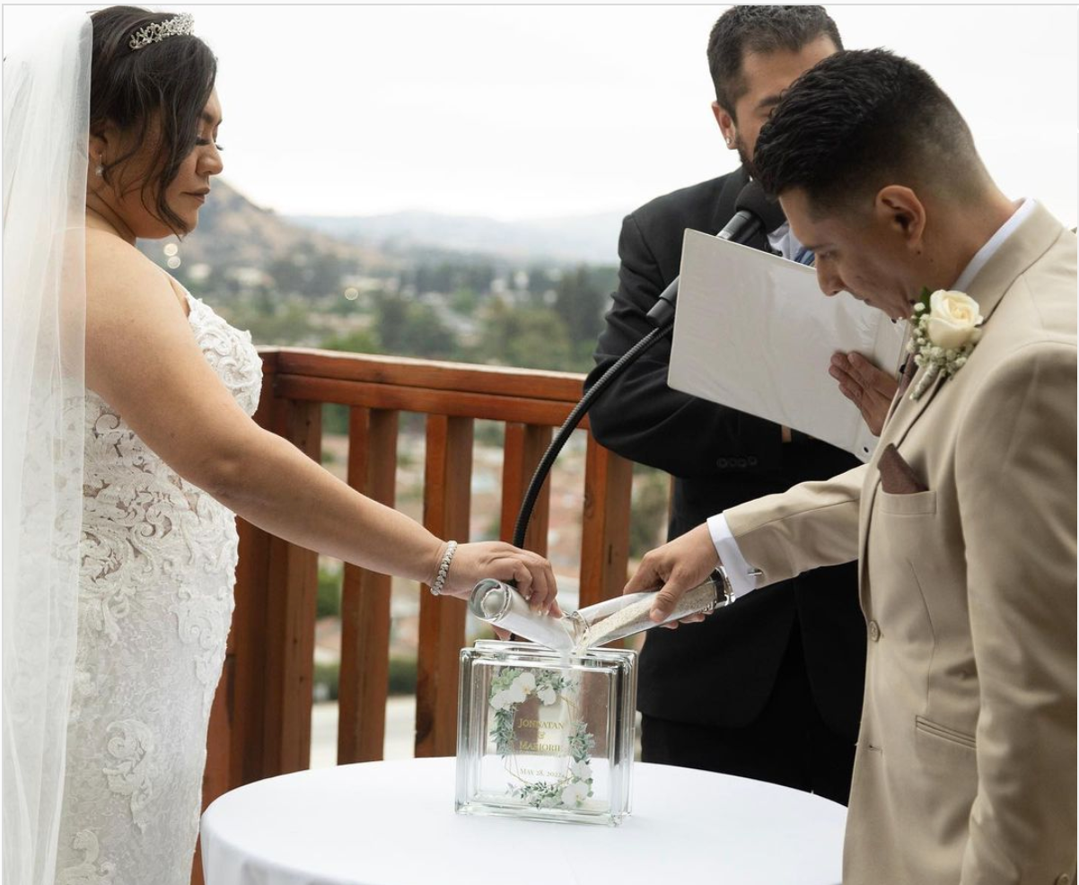 Couple performing a sand ceremony on an outdoor deck with panoramic views
